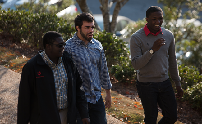 {Three young men walk across campus}